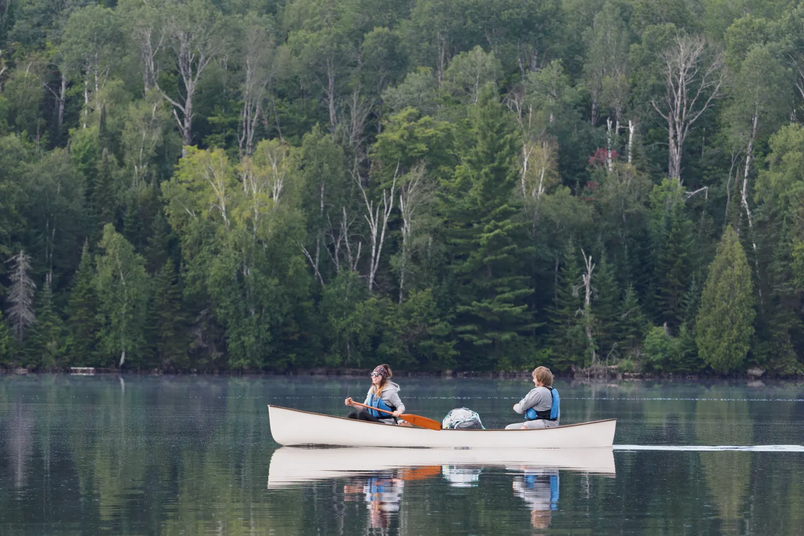Deux personnes en canoë sur un lac bordé de forêt