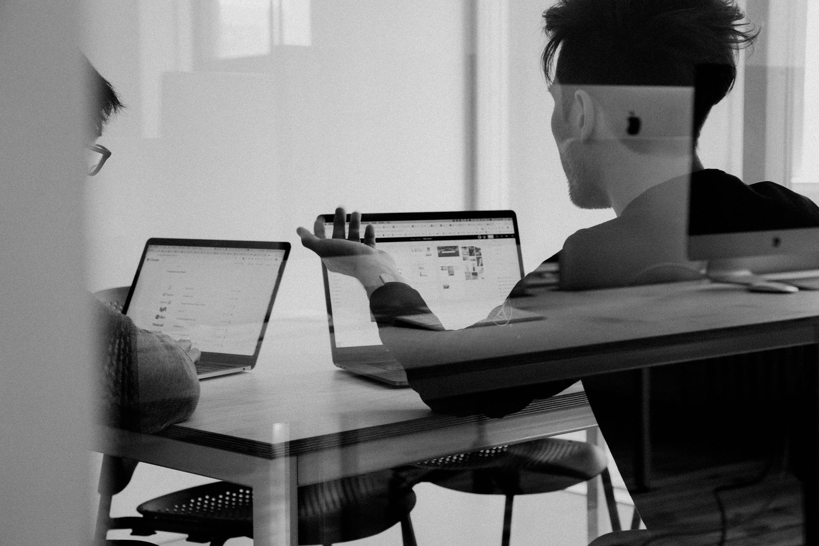 Deux personnes discutent d’un dossier de part et d’autre d’une table de travail.