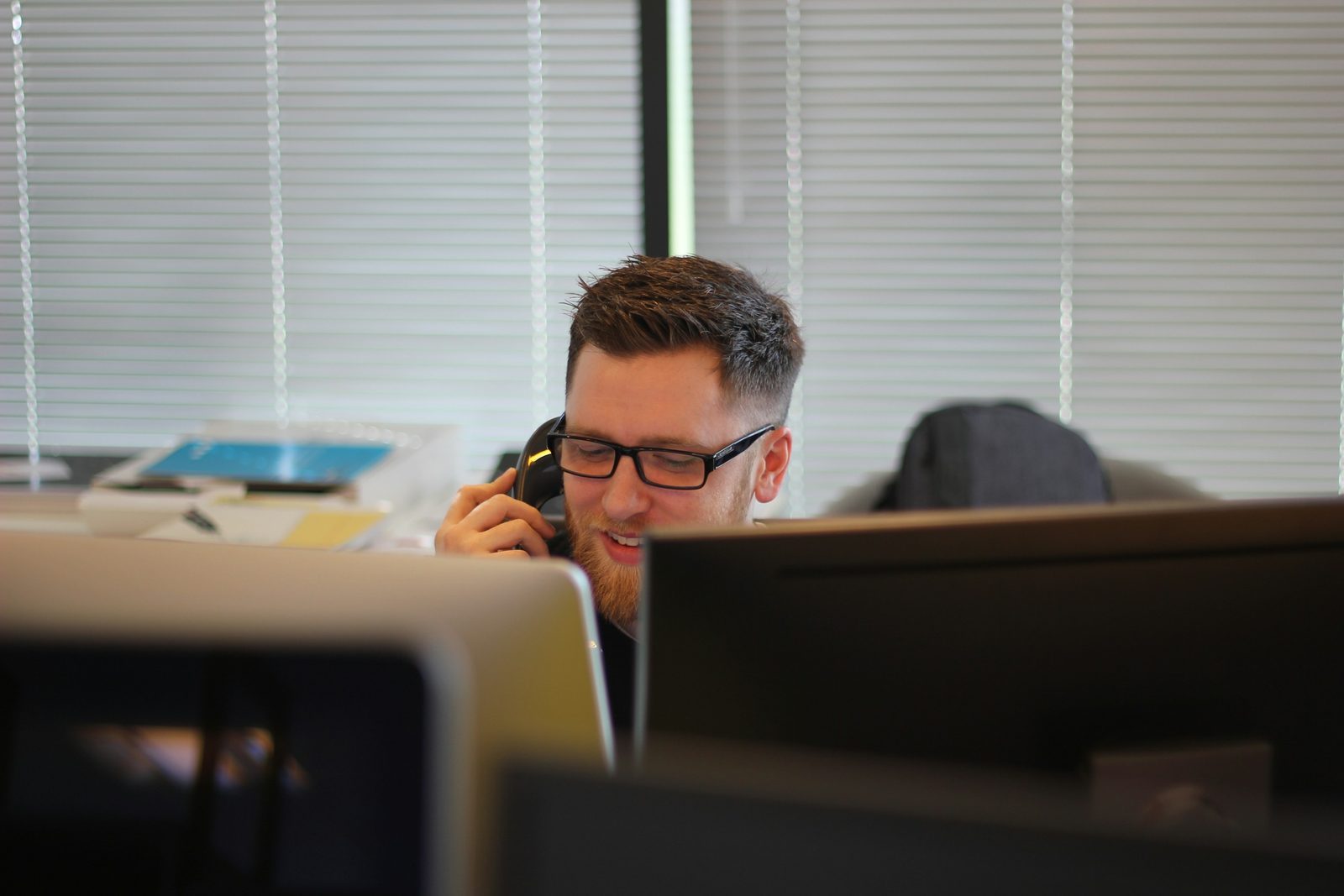 Un gestionnaire prend un appel à son poste de travail, dans un bureau en open space.